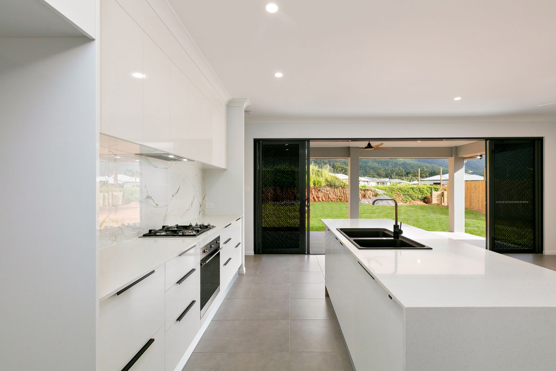 A Modern White Kitchen Featuring an Island — Ashlee Jones Homes in Gordonvale, QLD