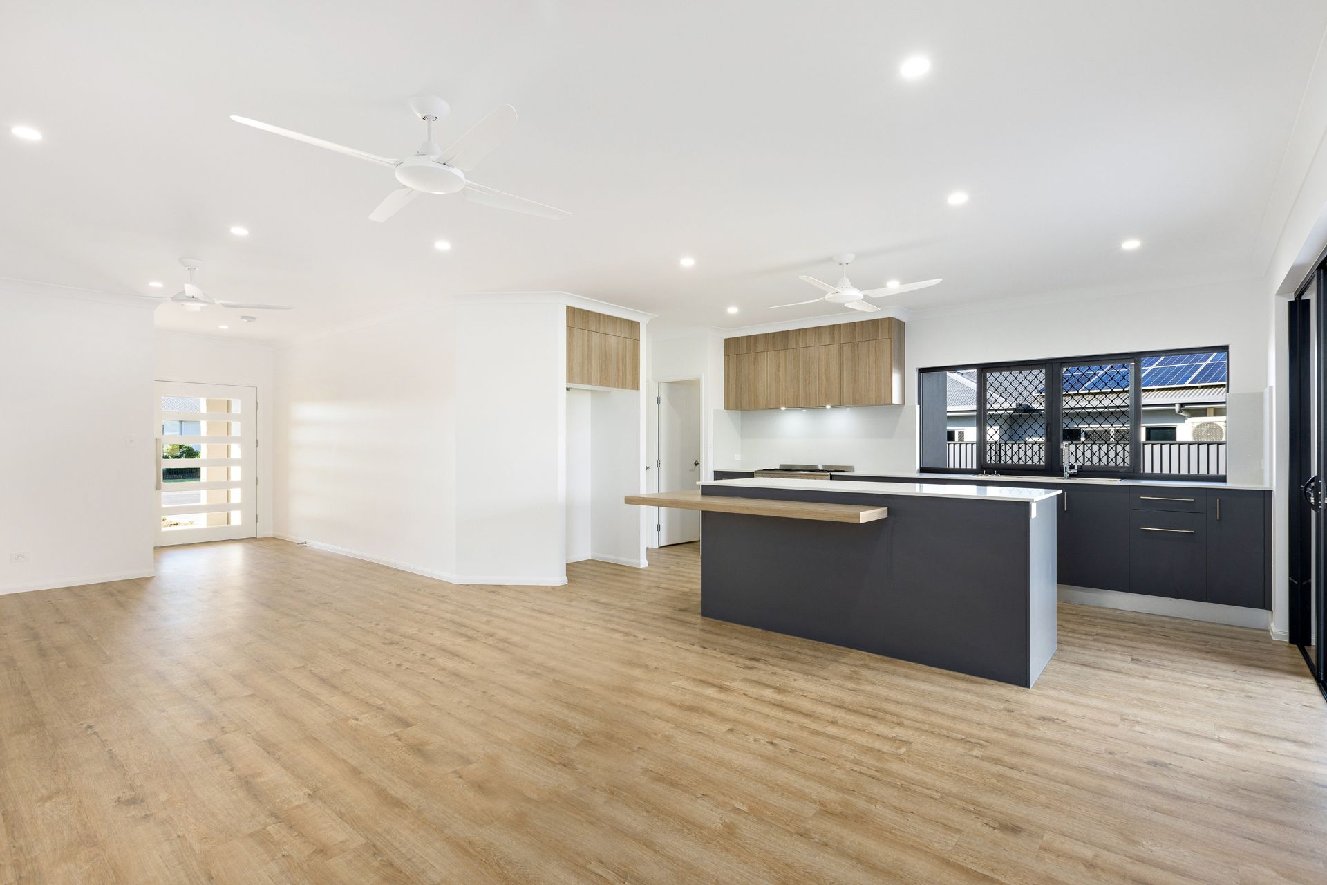 Modern Open-plan Kitchen and Living Space With a Dark Island — Ashlee Jones Homes in Gordonvale, QLD