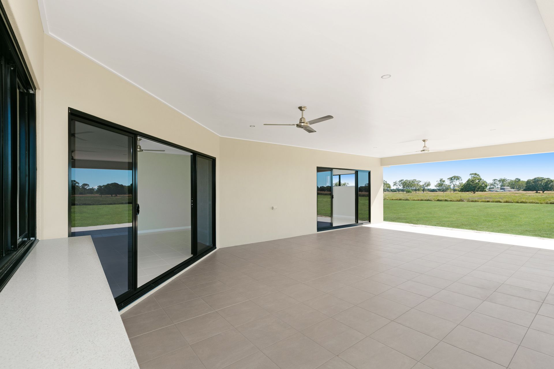 A Covered, Tiled Patio Overlooking a Grassy Field — Ashlee Jones Homes in Gordonvale, QLD