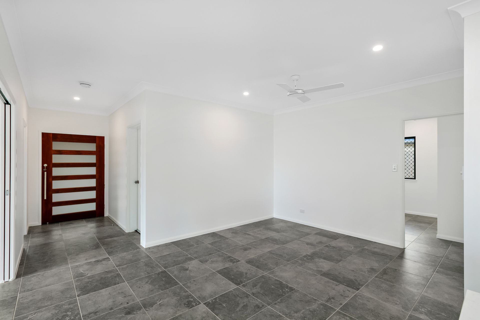 An Empty Room With Grey Tiled Flooring, White Walls — Ashlee Jones Homes in Gordonvale, QLD
