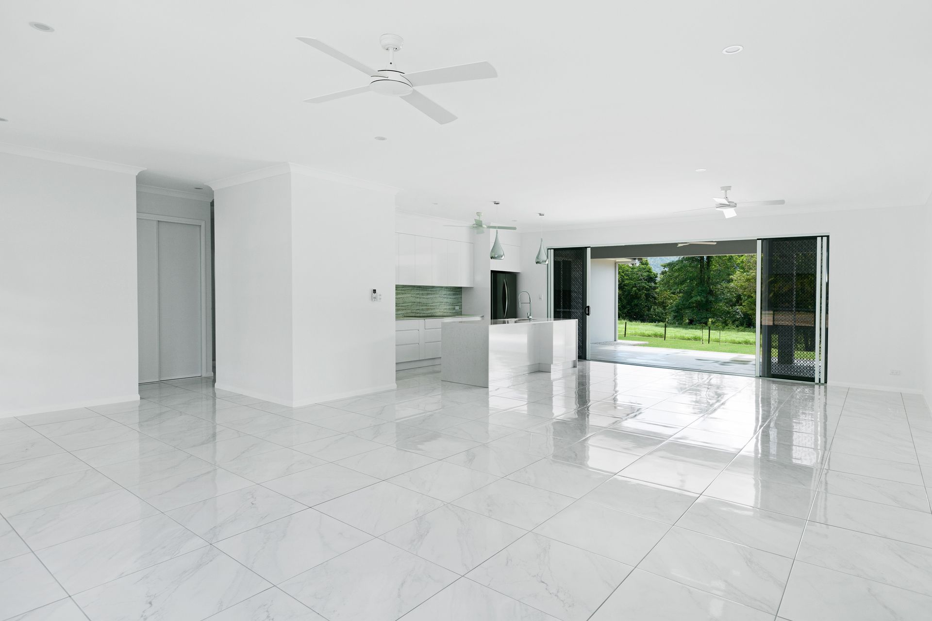 Bright, Open-plan Living and Kitchen Area With Glossy White Tile Floors — Ashlee Jones Homes in Gordonvale, QLD