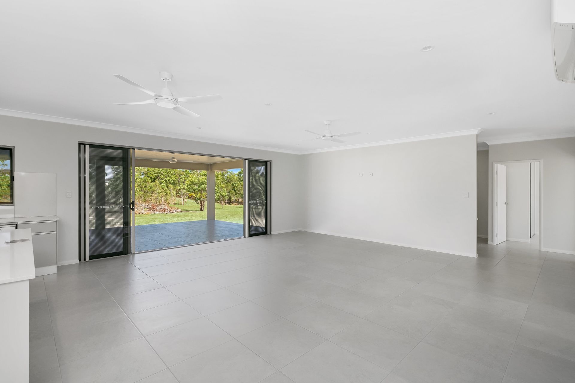 An Open-plan Living Area With Grey Tiled Floors — Ashlee Jones Homes in Gordonvale, QLD