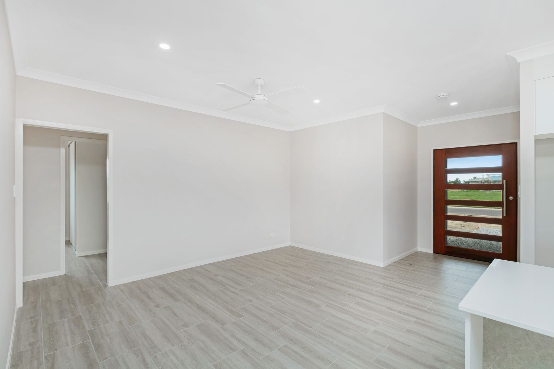 An Empty Room With Light Gray Wood-look Flooring, White Walls, a Ceiling Fan — Ashlee Jones Homes in Gordonvale, QLD