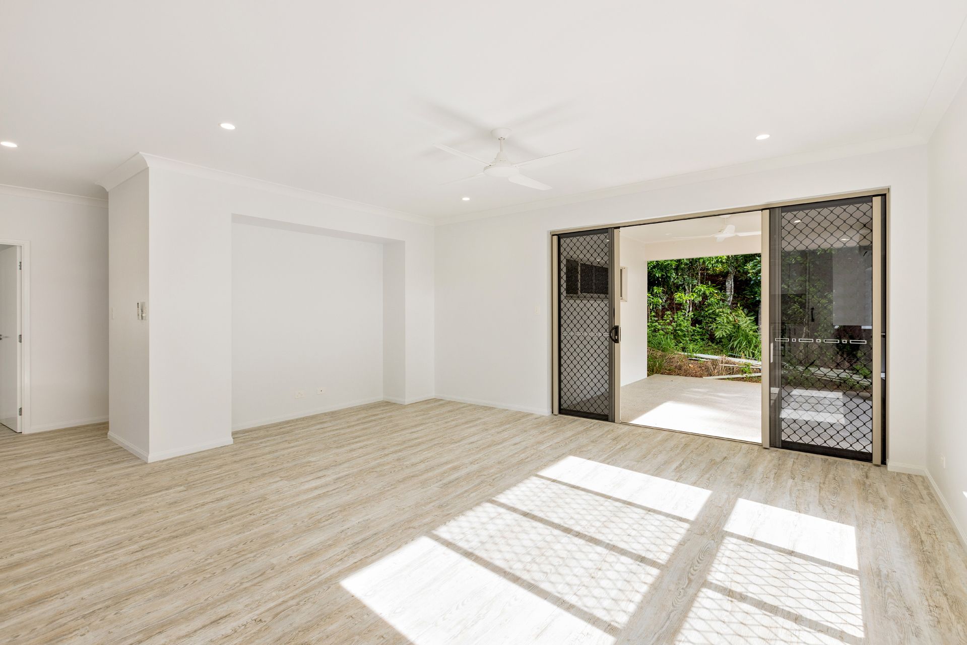 A Bright, Empty Living Room With Light Wood-look Floors — Ashlee Jones Homes in Gordonvale, QLD
