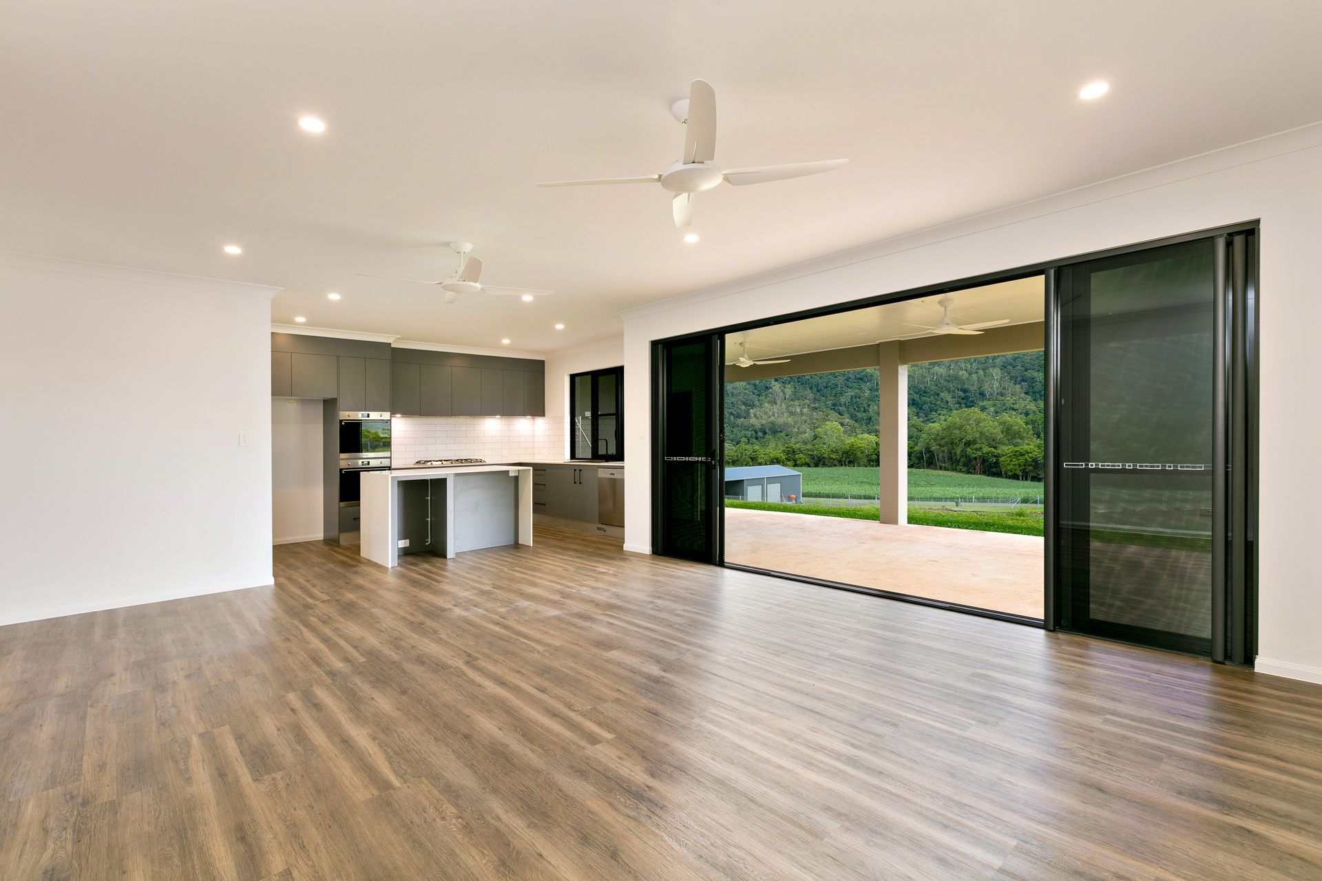 Open-plan Living Room With Wood-look Flooring — Ashlee Jones Homes in Gordonvale, QLD