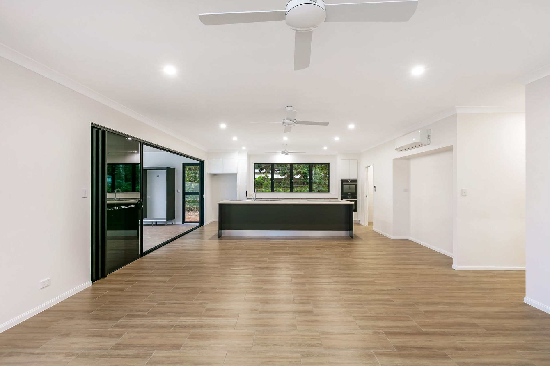 An Open-plan Living and Kitchen Area With Light Wood-look Flooring — Ashlee Jones Homes in Gordonvale, QLD