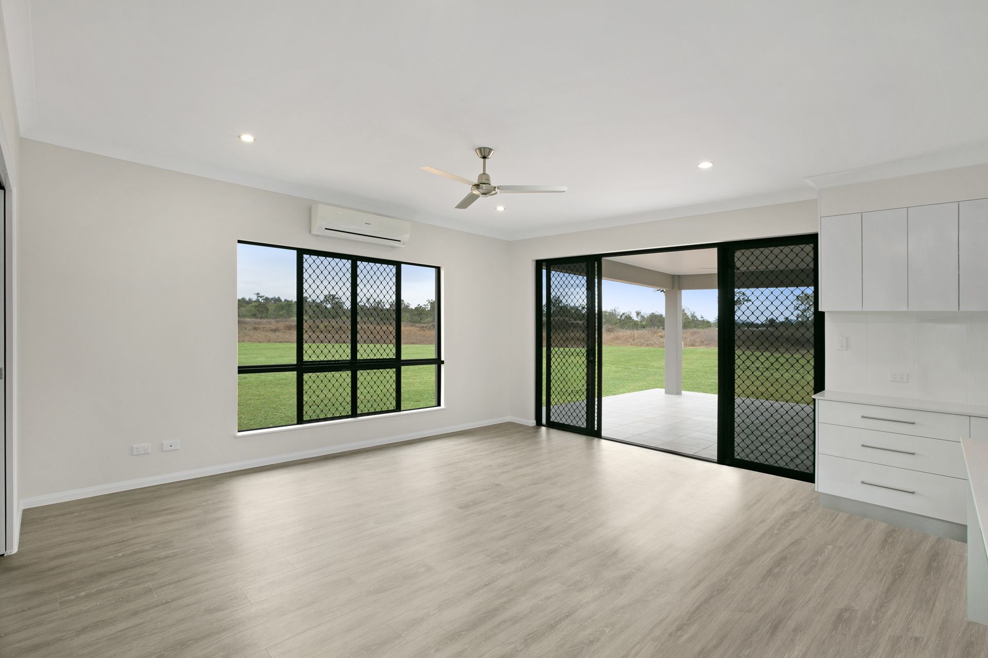 An Empty, Modern Living Space With Light Wood Floors — Ashlee Jones Homes in Gordonvale, QLD