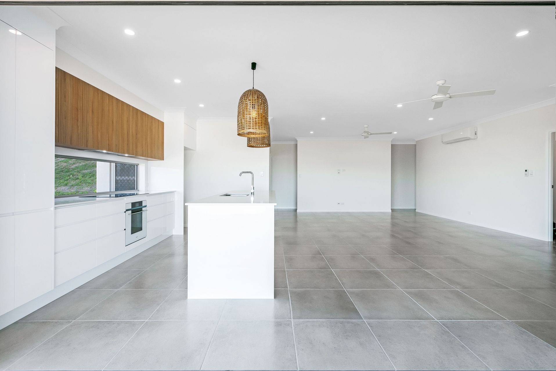 A Modern Open-plan Kitchen and Living Space With White Cabinets — Ashlee Jones Homes in Gordonvale, QLD