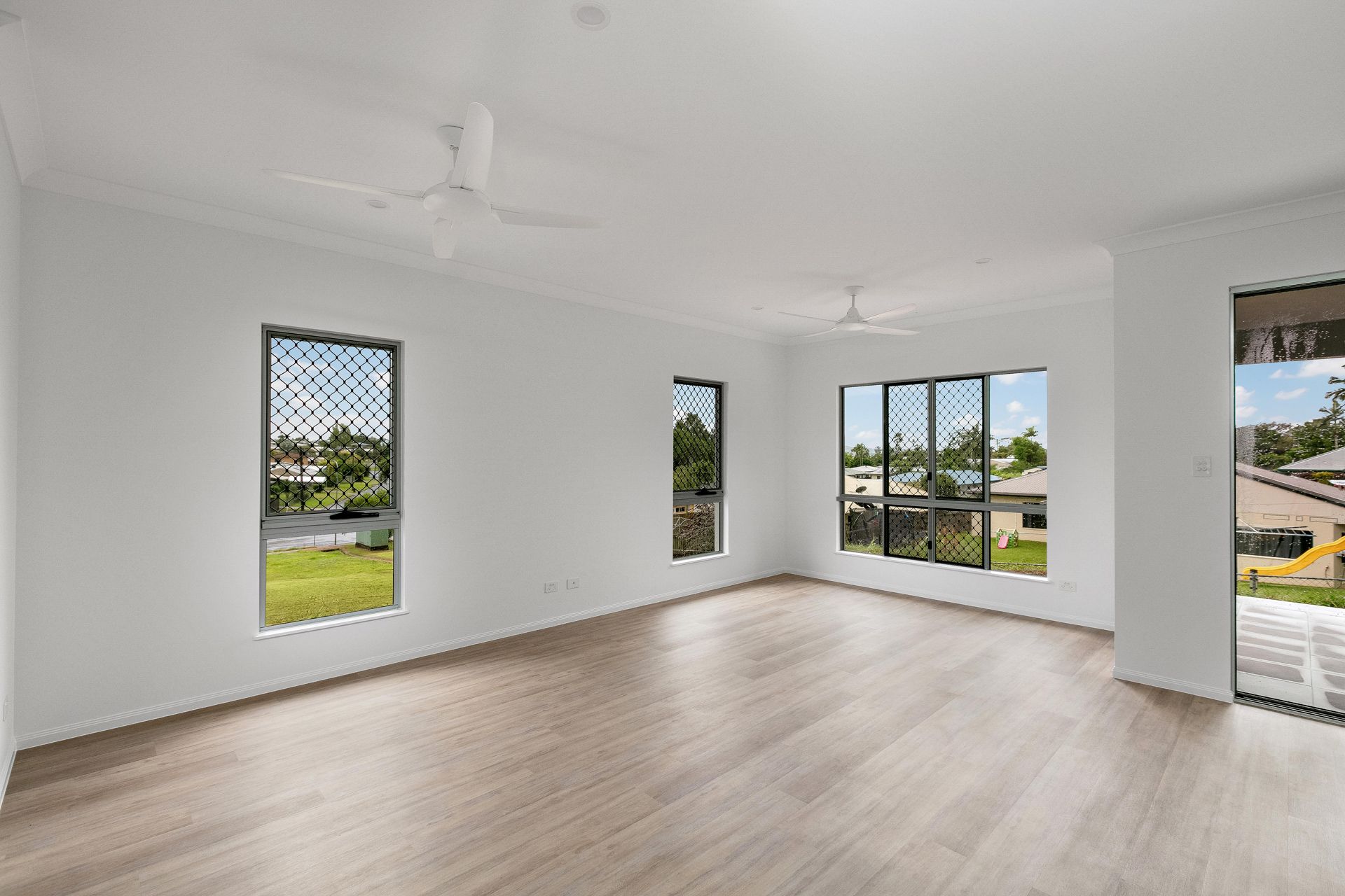 A Bright, Empty Room With Light-toned Wood Floors — Ashlee Jones Homes in Gordonvale, QLD