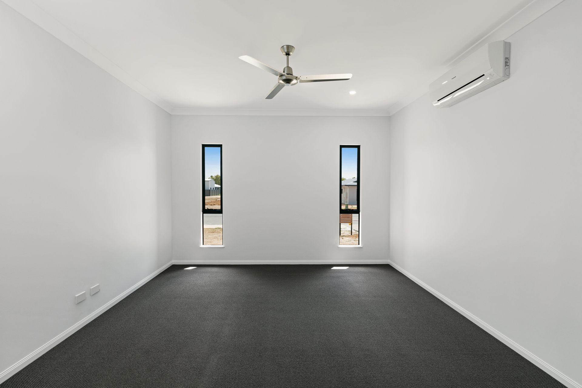 A Modern Empty Room With White Walls, Dark Gray Carpeting — Ashlee Jones Homes in Gordonvale, QLD