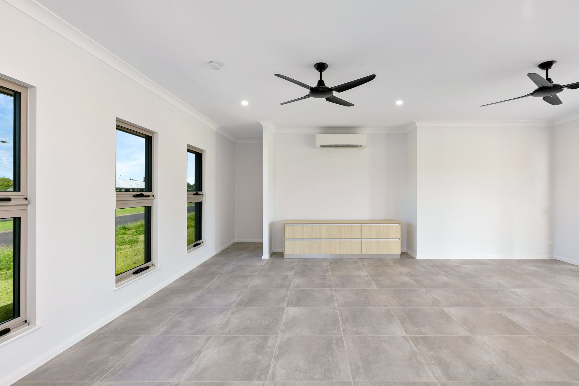 A Bright, Empty Room With Grey Tiled Floors — Ashlee Jones Homes in Gordonvale, QLD