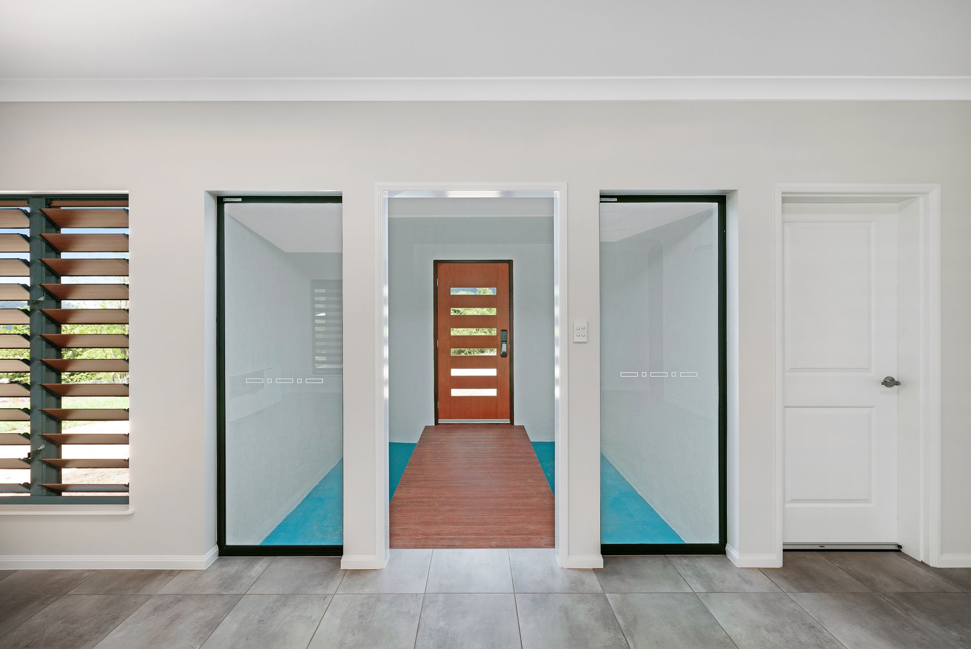 An Interior View of a Modern Hallway With a Wooden Front Door — Ashlee Jones Homes in Gordonvale, QLD