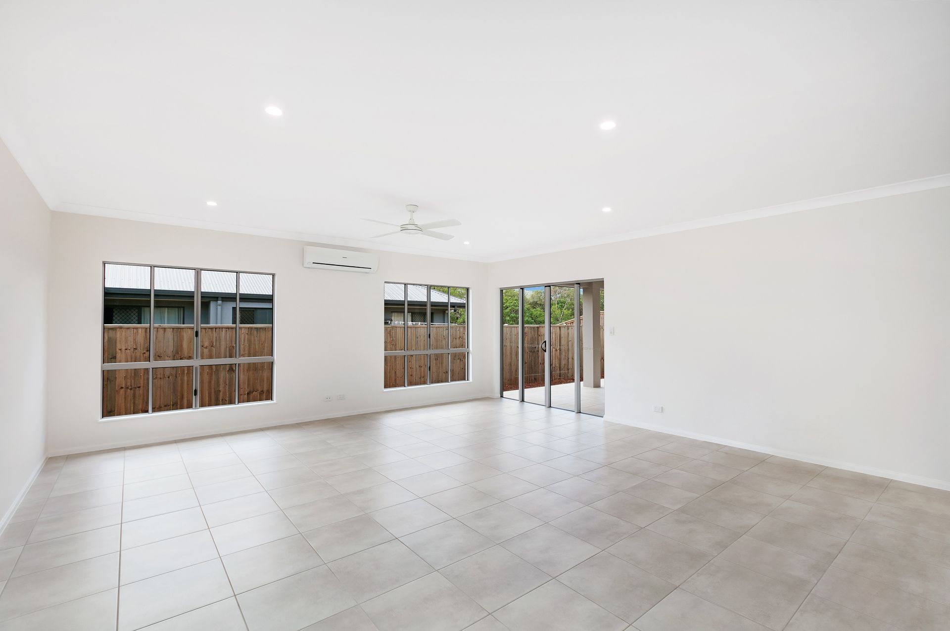 A Bright, Empty Living Room With Light Tiled Floors — Ashlee Jones Homes in Gordonvale, QLD