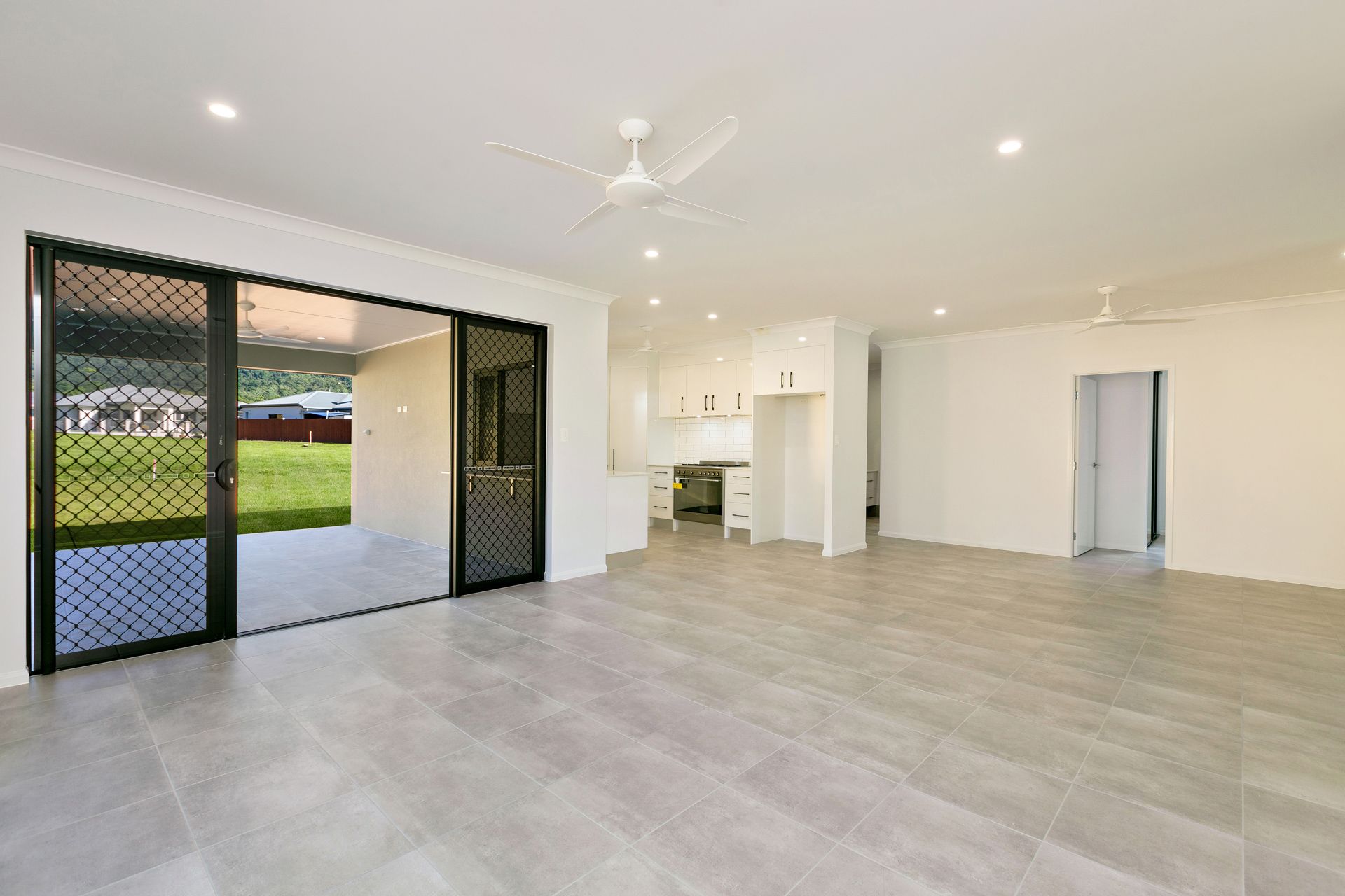 A Bright, Open-plan Living Room With Light Gray Tile Floors — Ashlee Jones Homes in Gordonvale, QLD