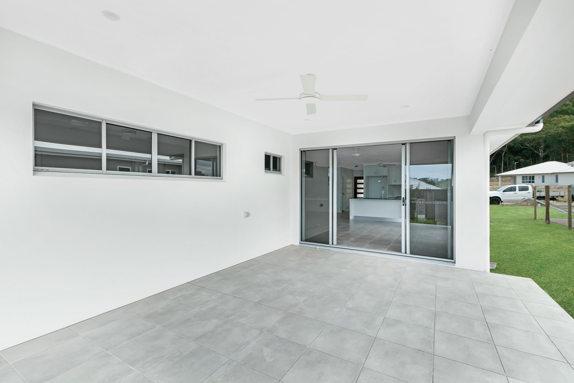 A Bright, Empty Covered Outdoor Patio With Light Gray Tile Flooring — Ashlee Jones Homes in Gordonvale, QLD
