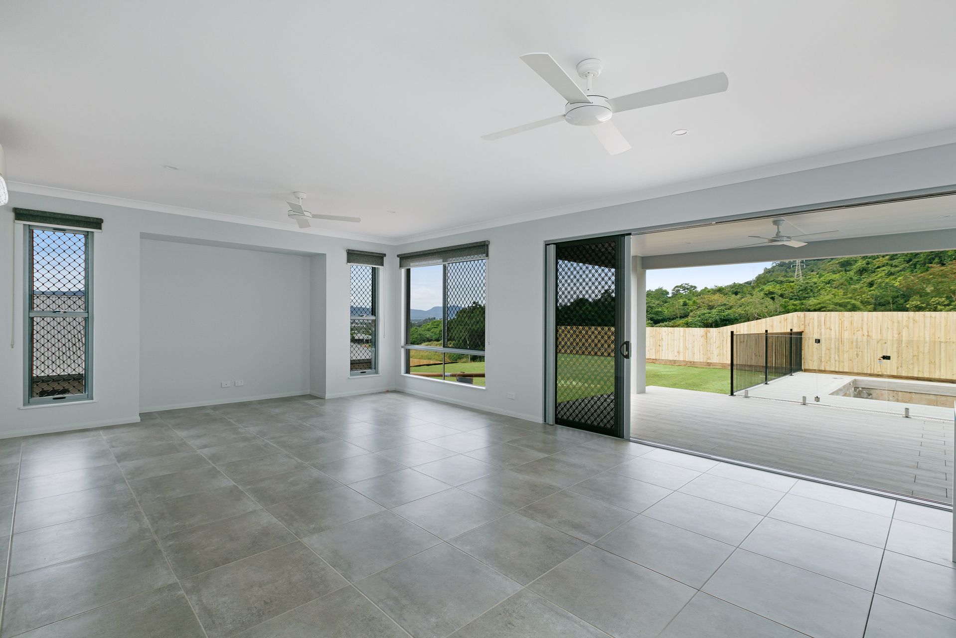 A Spacious Room With Grey Tiled Floors, White Walls — Ashlee Jones Homes in Gordonvale, QLD