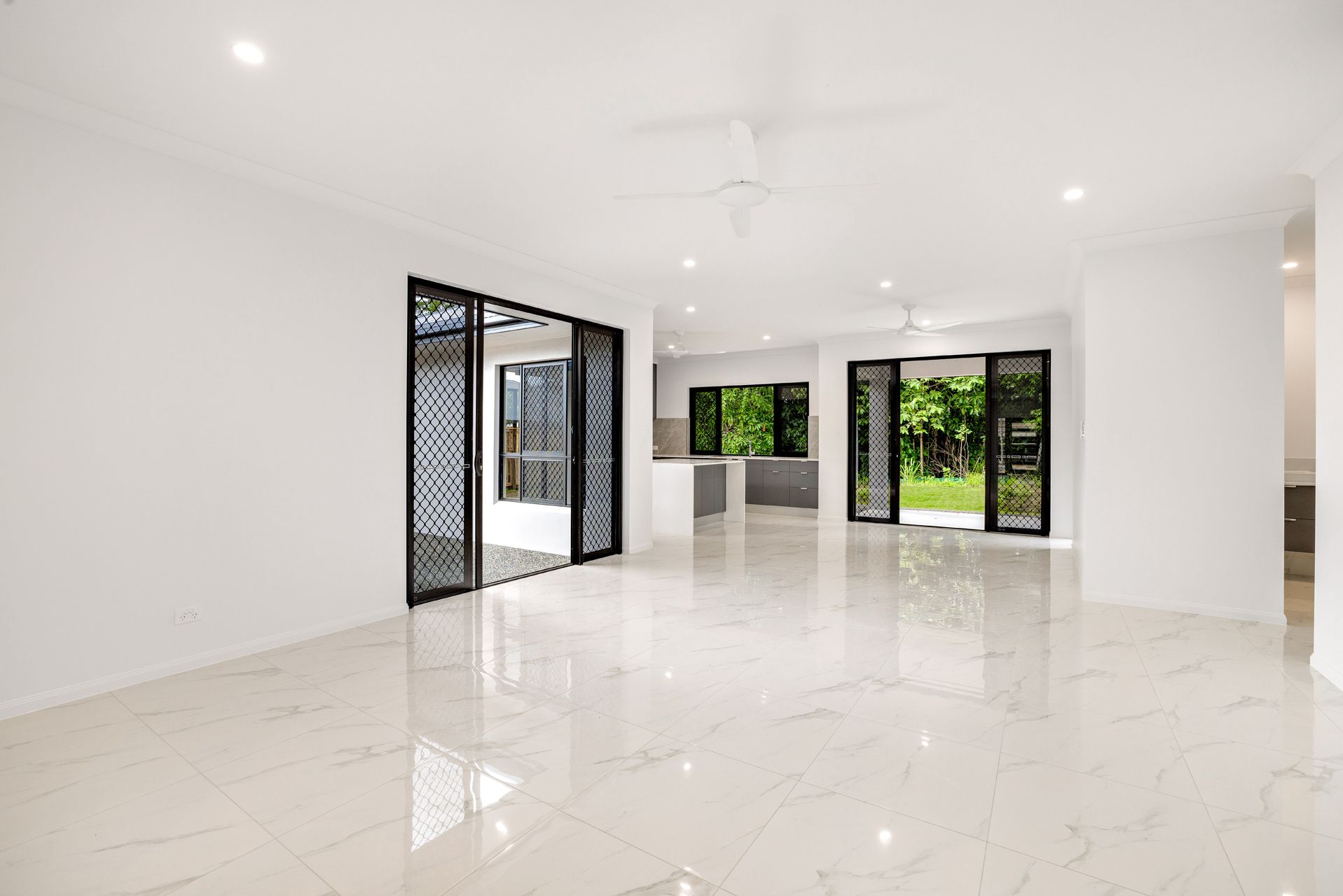 An Expansive, White, Open-plan Living Area With Polished Marble-look Floors — Ashlee Jones Homes in Gordonvale, QLD