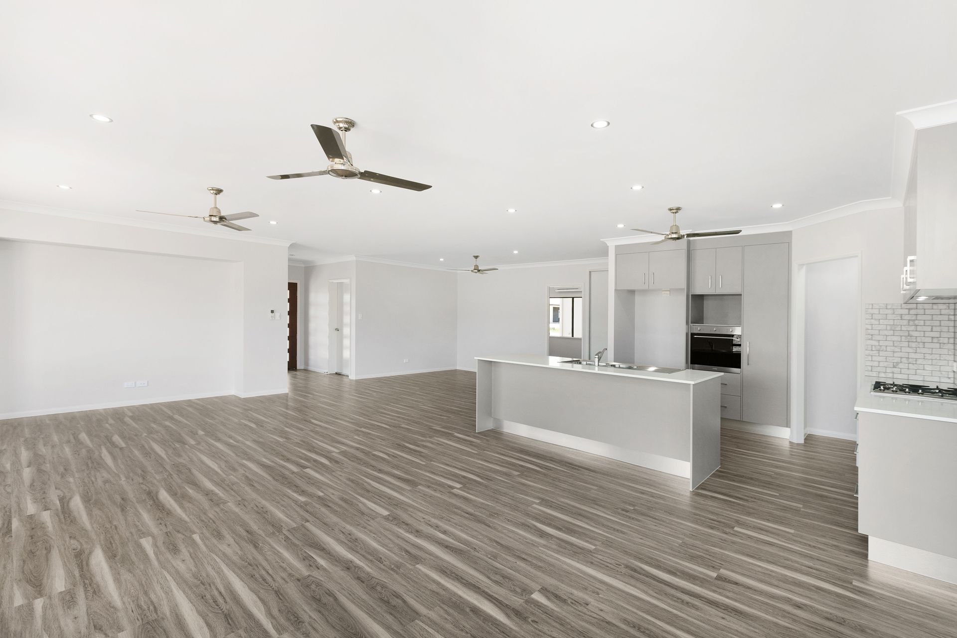 A Spacious, Modern Open-plan Room With Grey Wood-look Flooring — Ashlee Jones Homes in Gordonvale, QLD