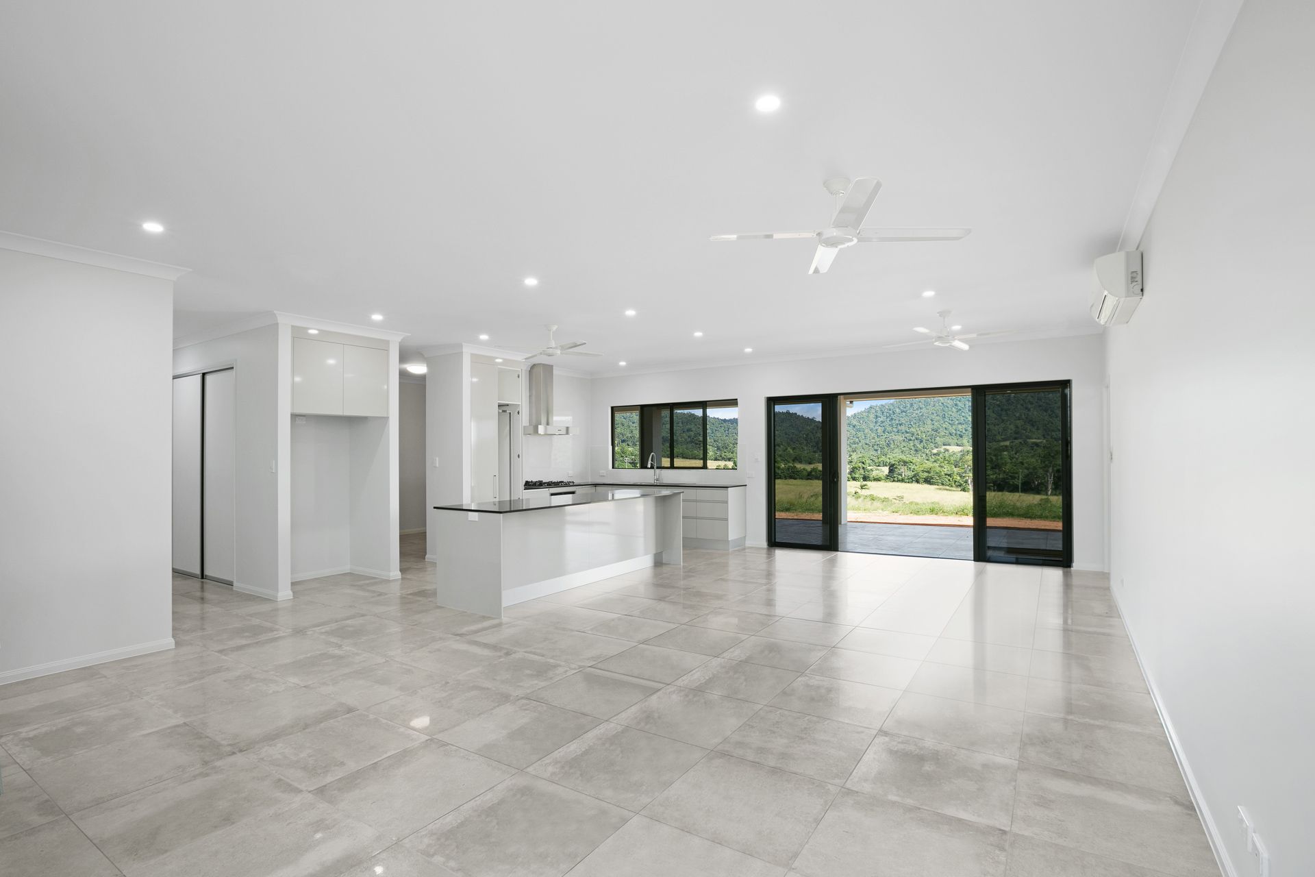 An Open-plan Living and Kitchen Area With Light Gray Tile Floors — Ashlee Jones Homes in Gordonvale, QLD