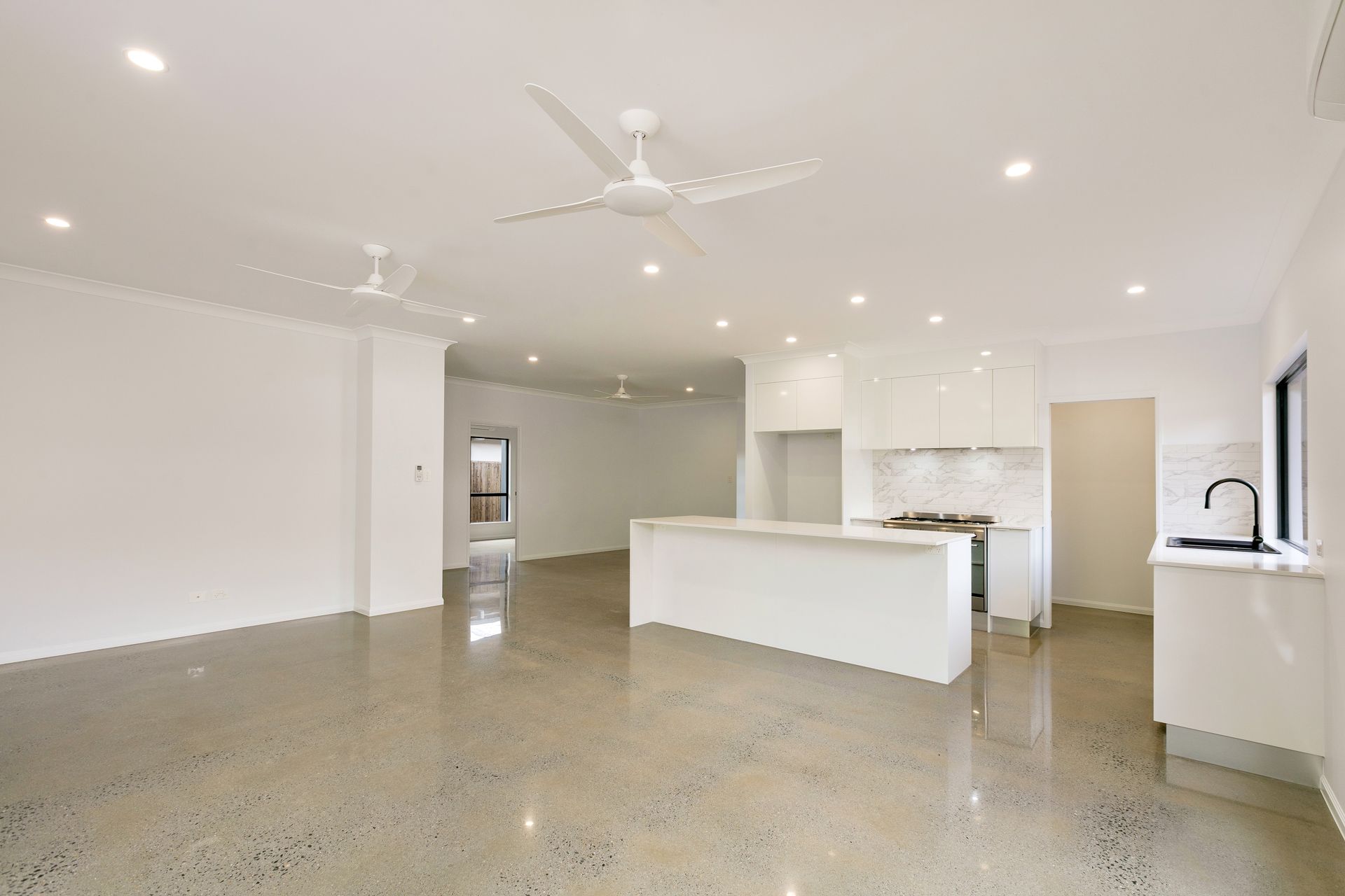 A Modern, Minimalist Open-plan Living and Kitchen Area With White Walls — Ashlee Jones Homes in Gordonvale, QLD