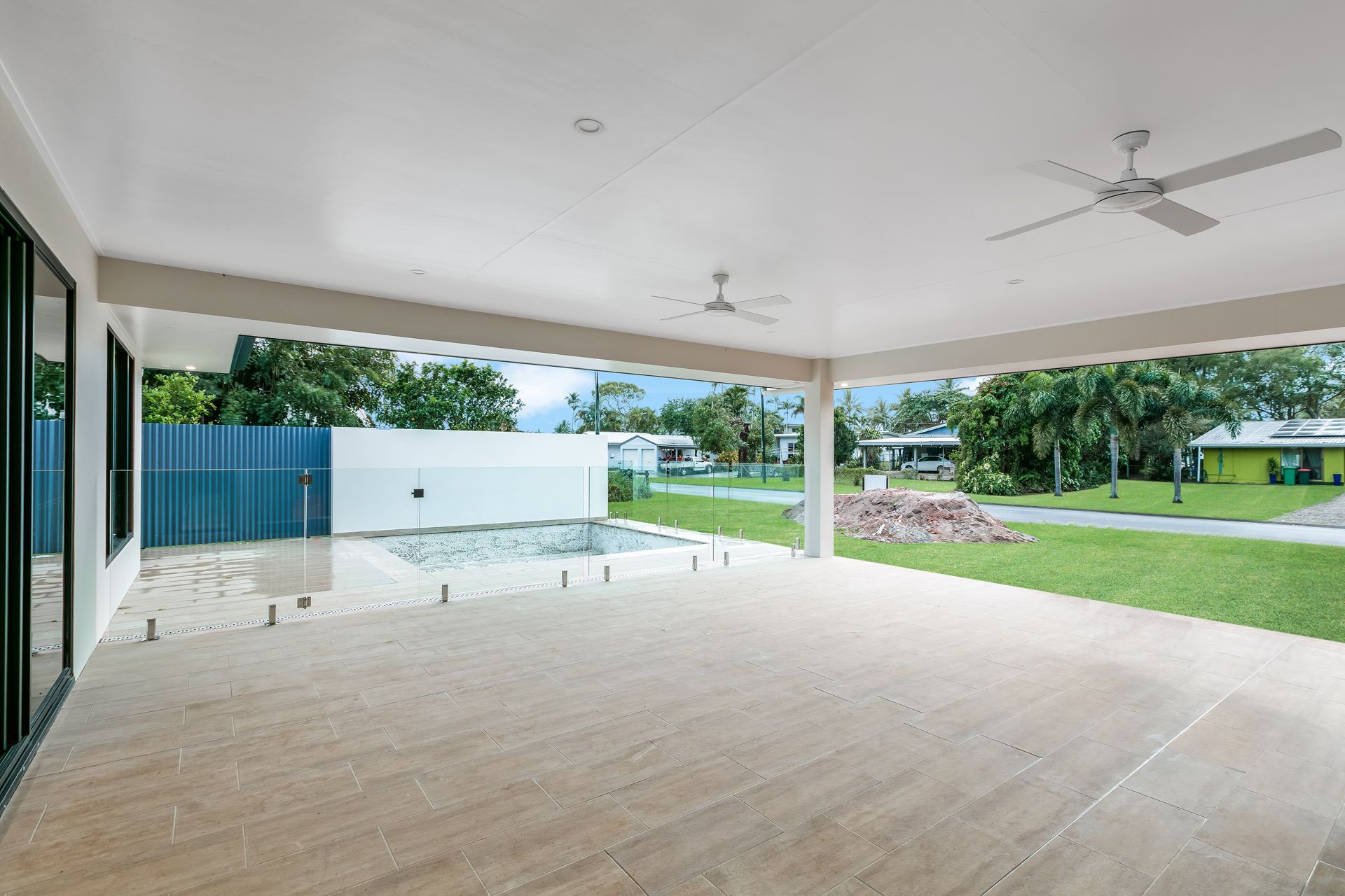 A Spacious, Covered Outdoor Patio With Light-colored Tile Floors — Ashlee Jones Homes in Gordonvale, QLD