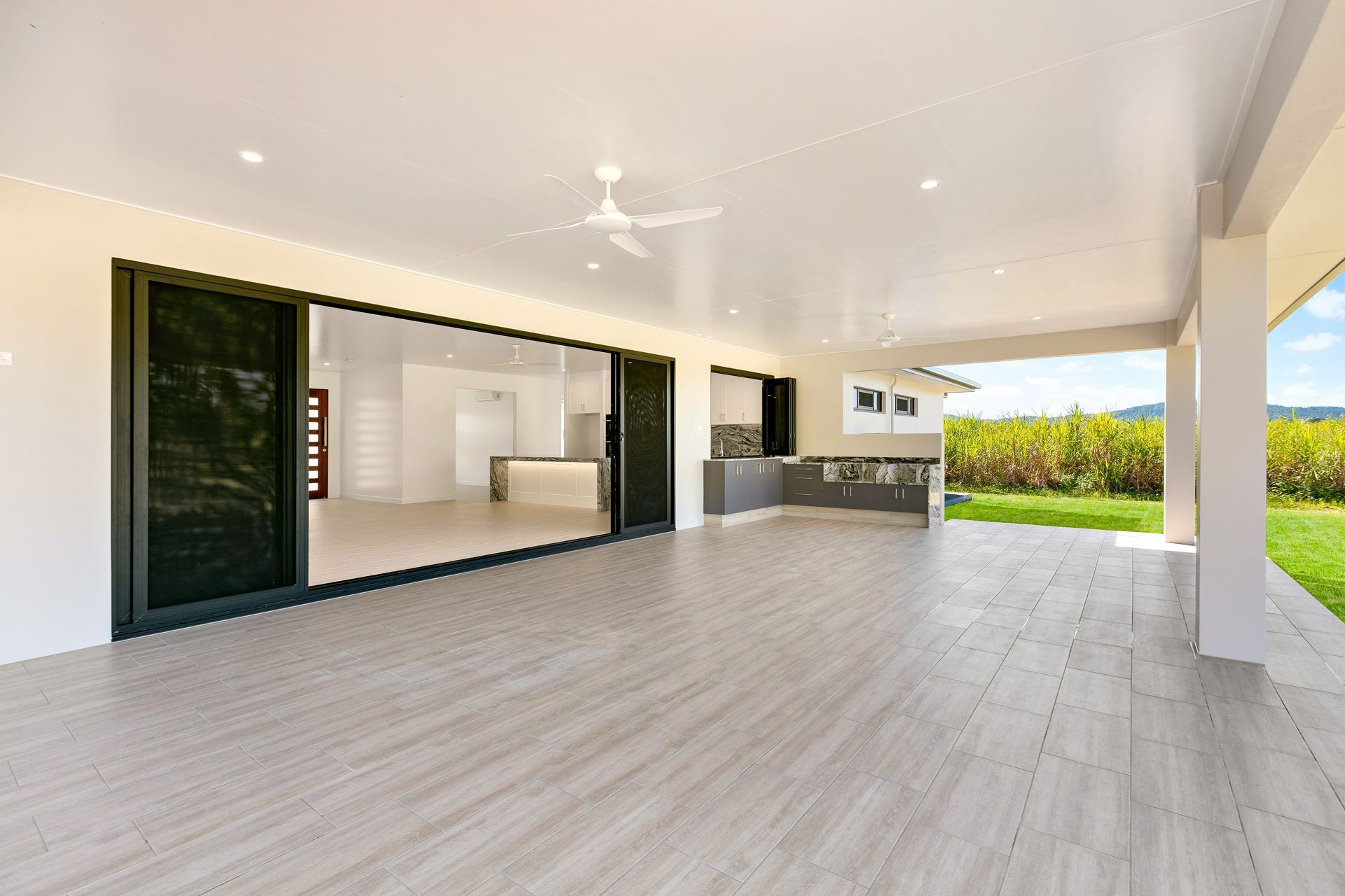 Spacious Outdoor Patio With Light Wood-look Tiled Floors — Ashlee Jones Homes in Gordonvale, QLD