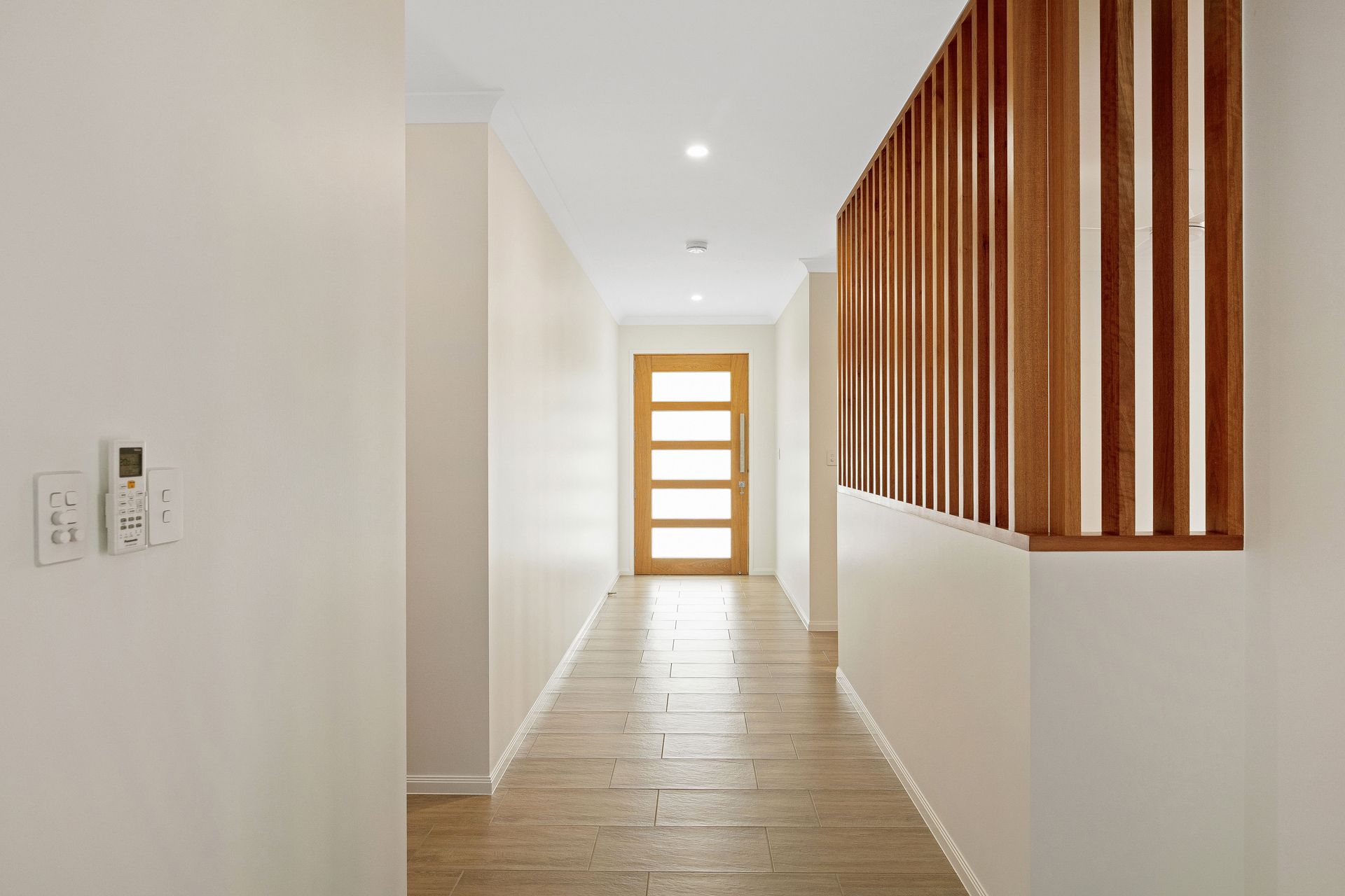 A Modern Hallway With Light Wood Floors, White Walls — Ashlee Jones Homes in Gordonvale, QLD