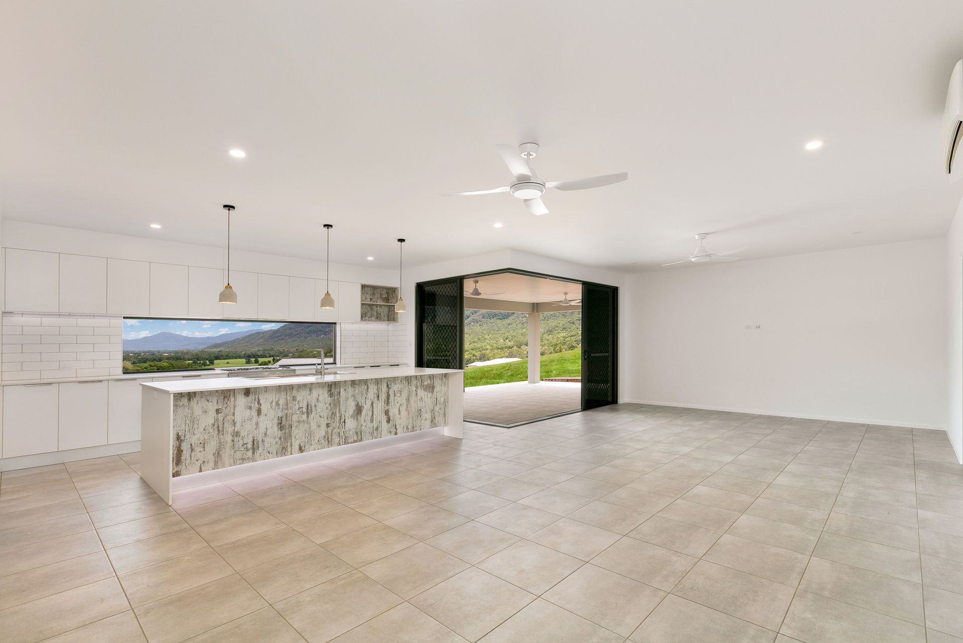 A Modern, Open-plan Kitchen and Living Area Featuring White Cabinets — Ashlee Jones Homes in Gordonvale, QLD