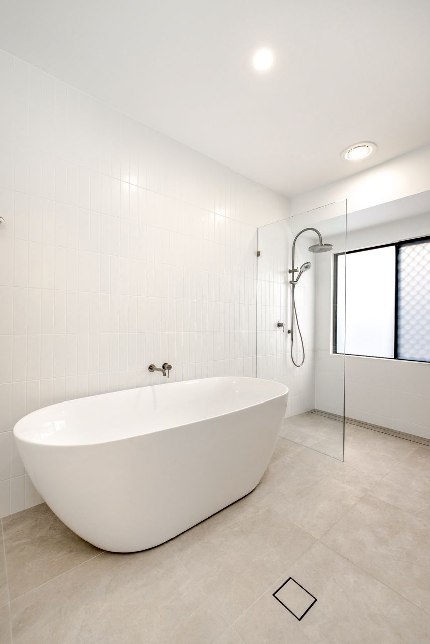 A Modern Bathroom Featuring a White Freestanding Bathtub — Ashlee Jones Homes in Gordonvale, QLD