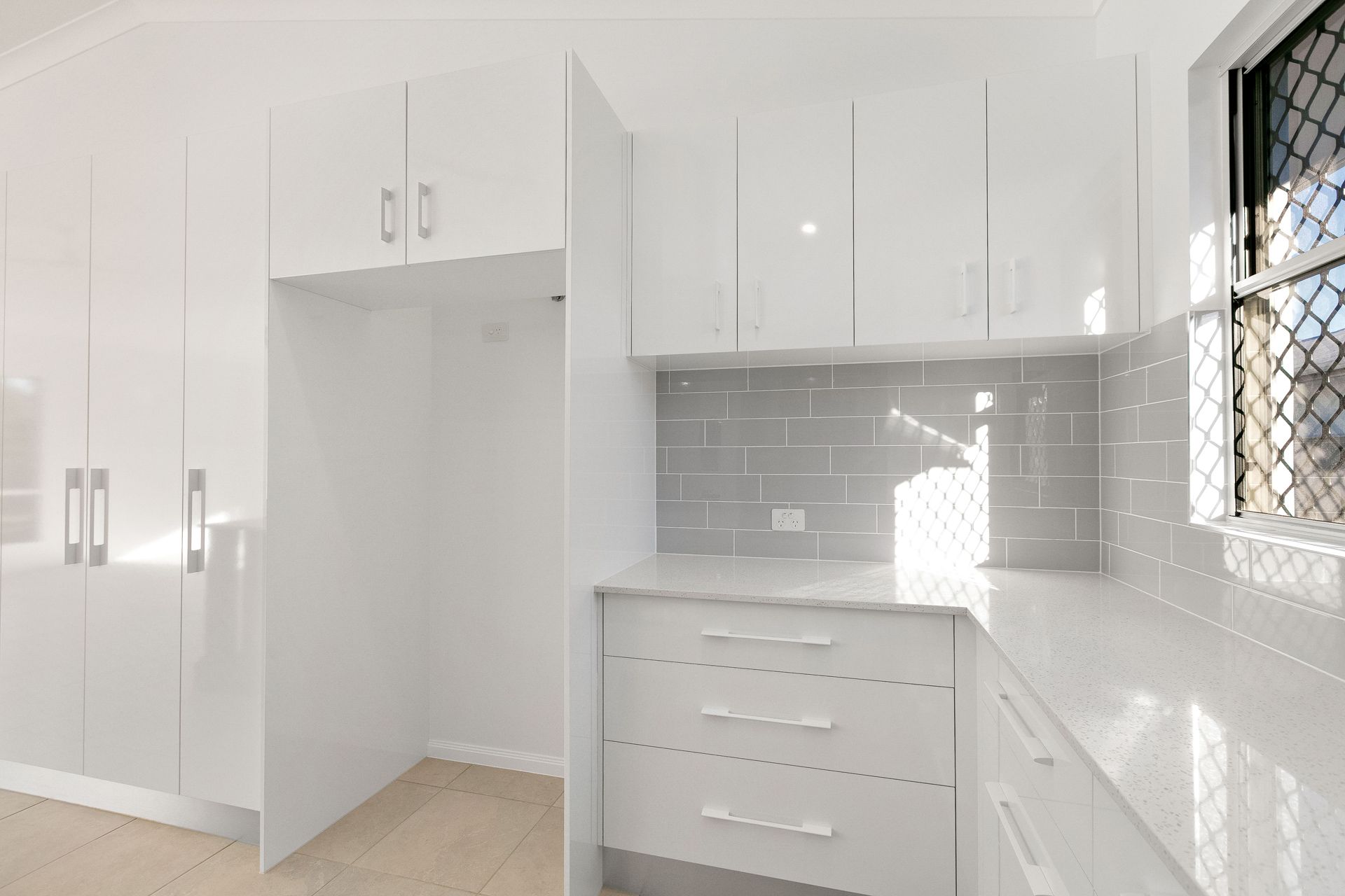 A Modern White Kitchen Featuring Glossy Cabinets — Ashlee Jones Homes in Gordonvale, QLD