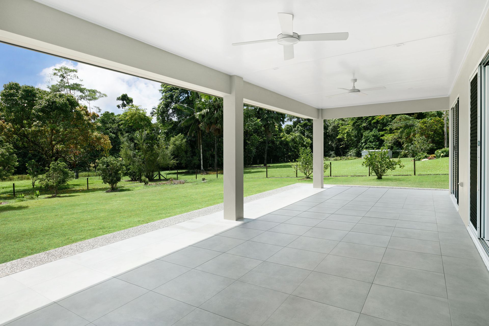A Spacious Covered Patio With Grey Tiled Flooring — Ashlee Jones Homes in Gordonvale, QLD