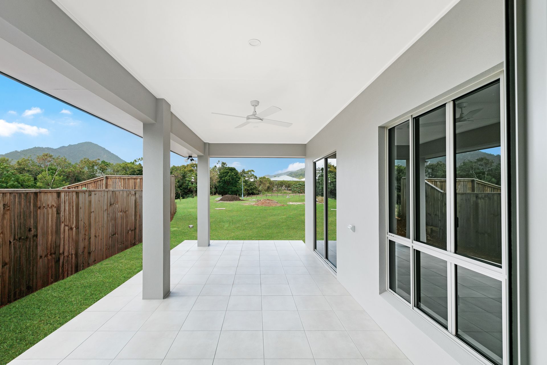 A Covered White Patio With Tiled Floors, a Ceiling Fan — Ashlee Jones Homes in Gordonvale, QLD