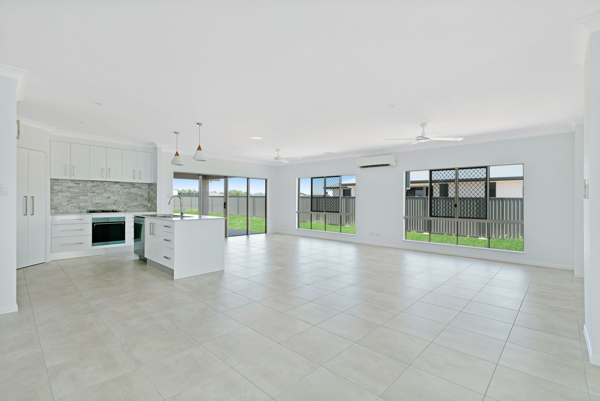 A Bright, Open-plan Kitchen and Living Area With White Walls — Ashlee Jones Homes in Gordonvale, QLD