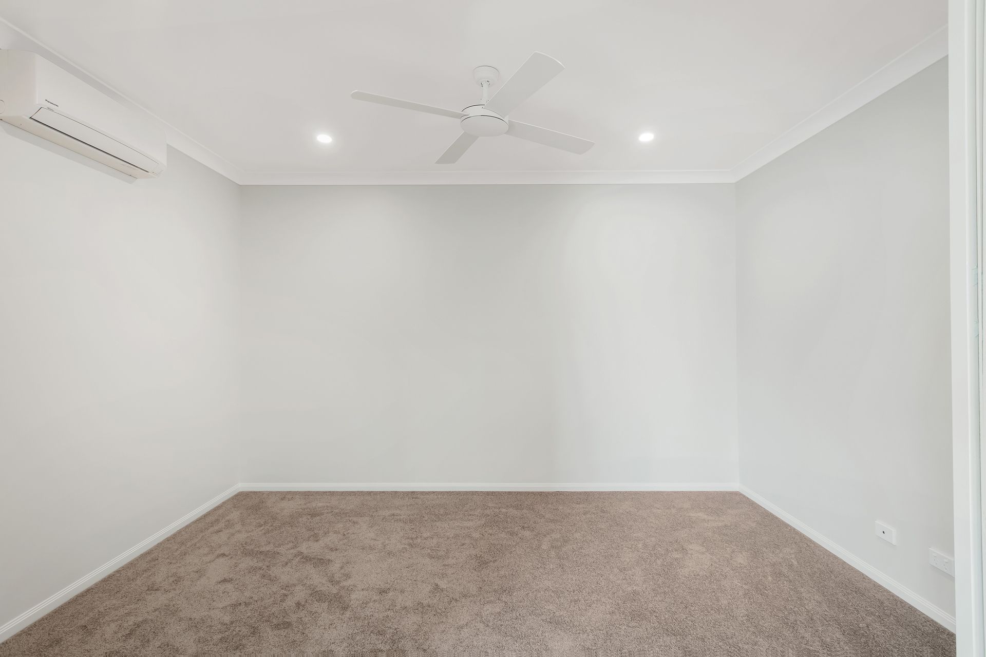 A Minimalist, Empty Room With Grey Carpet, Light Grey Walls — Ashlee Jones Homes in Gordonvale, QLD