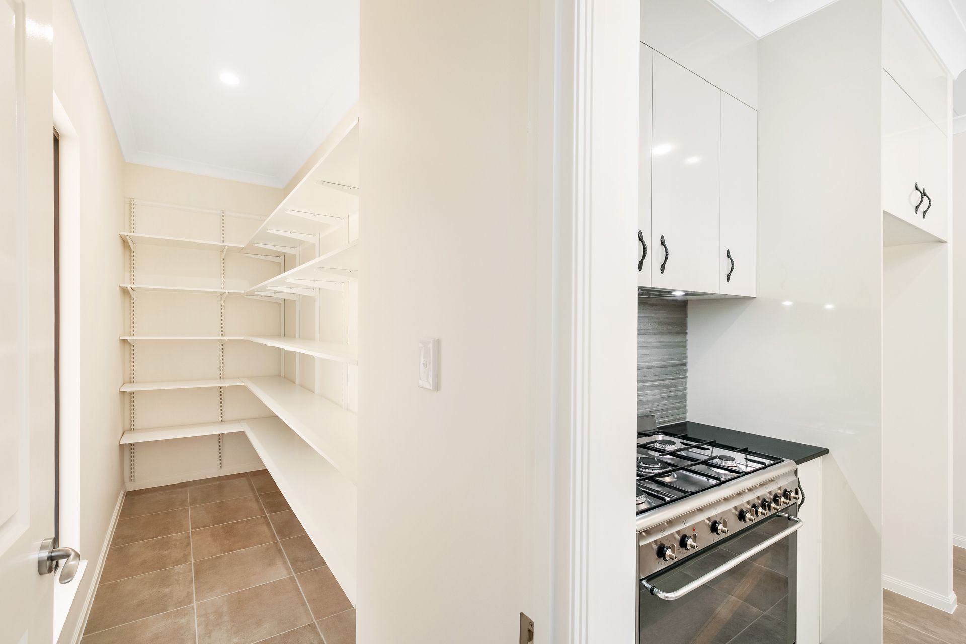 A Brightly Lit Pantry With Open White Shelving — Ashlee Jones Homes in Gordonvale, QLD