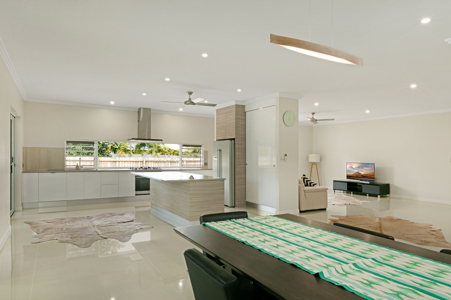 A Modern Open-plan Home Interior Featuring a Kitchen With a Stone Island — Ashlee Jones Homes in Gordonvale, QLD