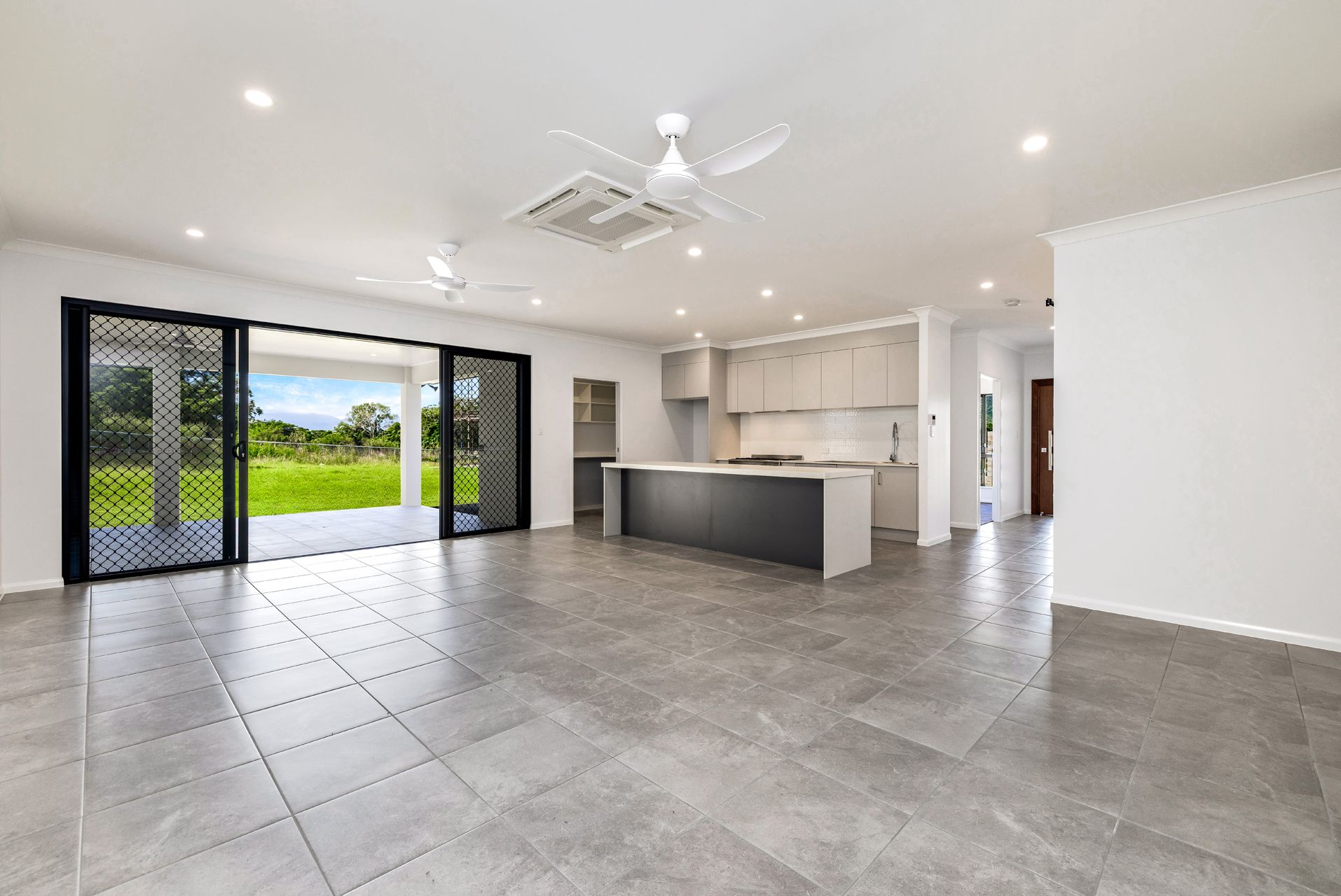 Modern Open-plan Kitchen and Living Area With Grey Tiled Floors — Ashlee Jones Homes in Gordonvale, QLD
