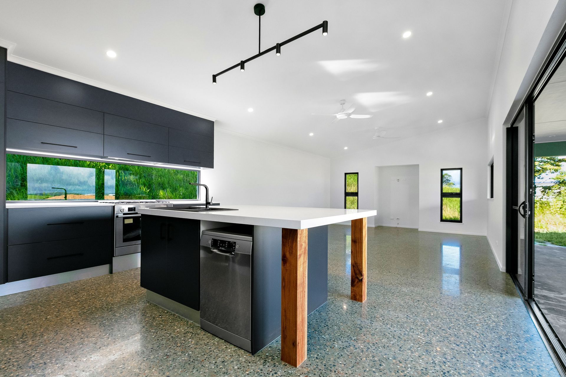 A Modern Kitchen Features Dark Charcoal Cabinets — Ashlee Jones Homes in Gordonvale, QLD