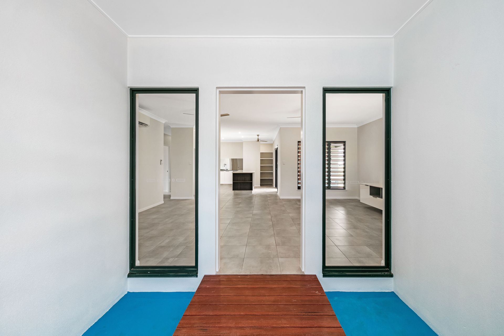 A Doorway Leads Into an Open-plan House With Gray Tile Floors — Ashlee Jones Homes in Gordonvale, QLD