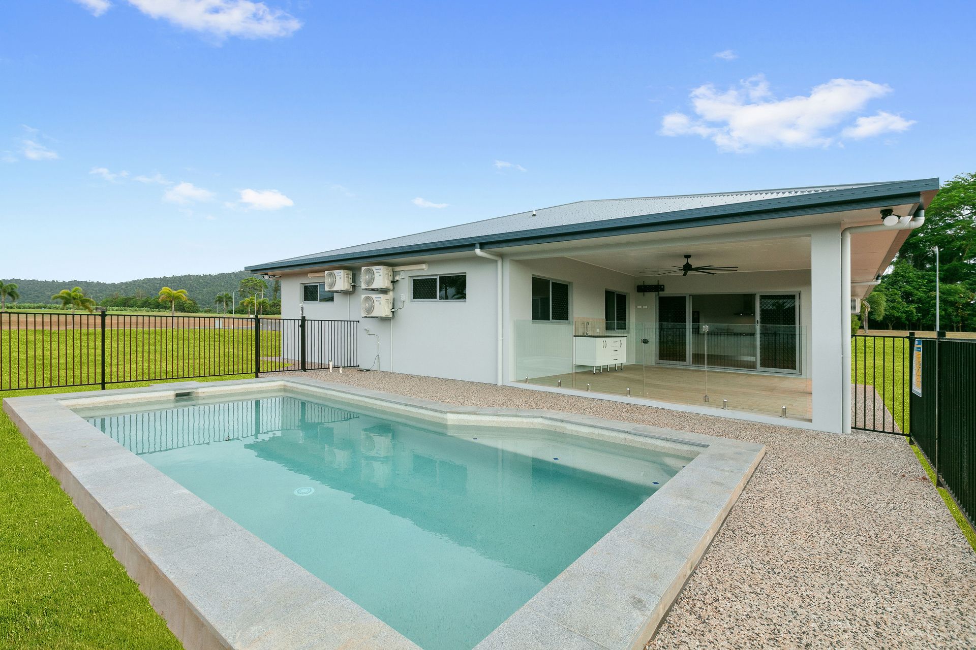 A Rectangular Swimming Pool Sits Next to a White House — Ashlee Jones Homes in Gordonvale, QLD