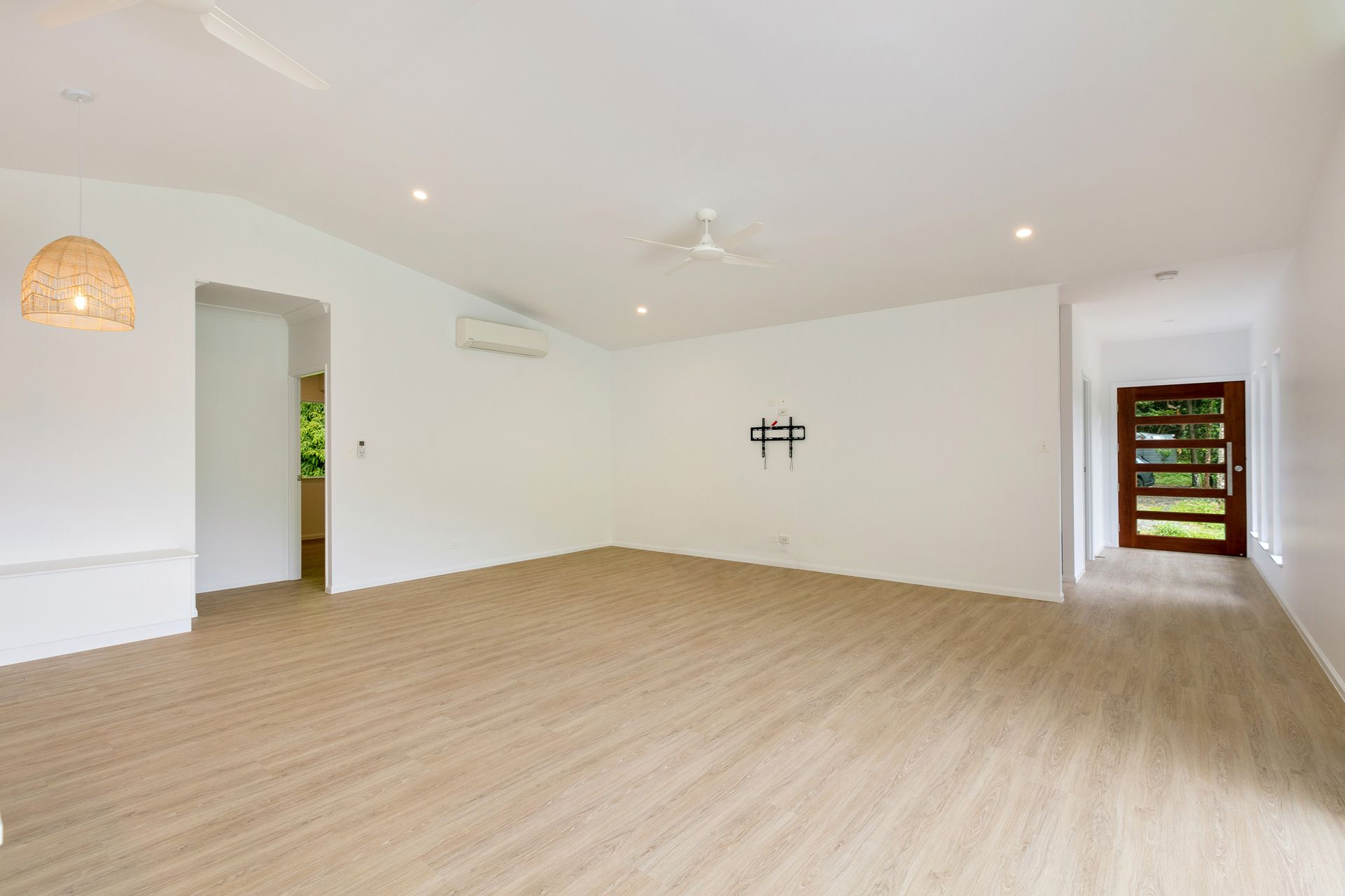 An Open, Bright, White-walled Living Room With Light Wood Flooring — Ashlee Jones Homes in Gordonvale, QLD
