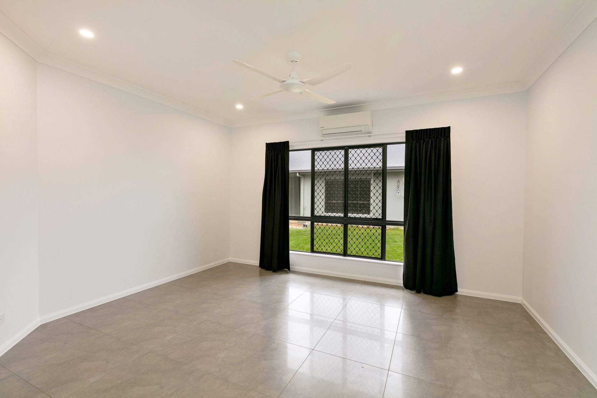 An Empty, Well-lit Room With White Walls, Grey Tile Flooring — Ashlee Jones Homes in Gordonvale, QLD