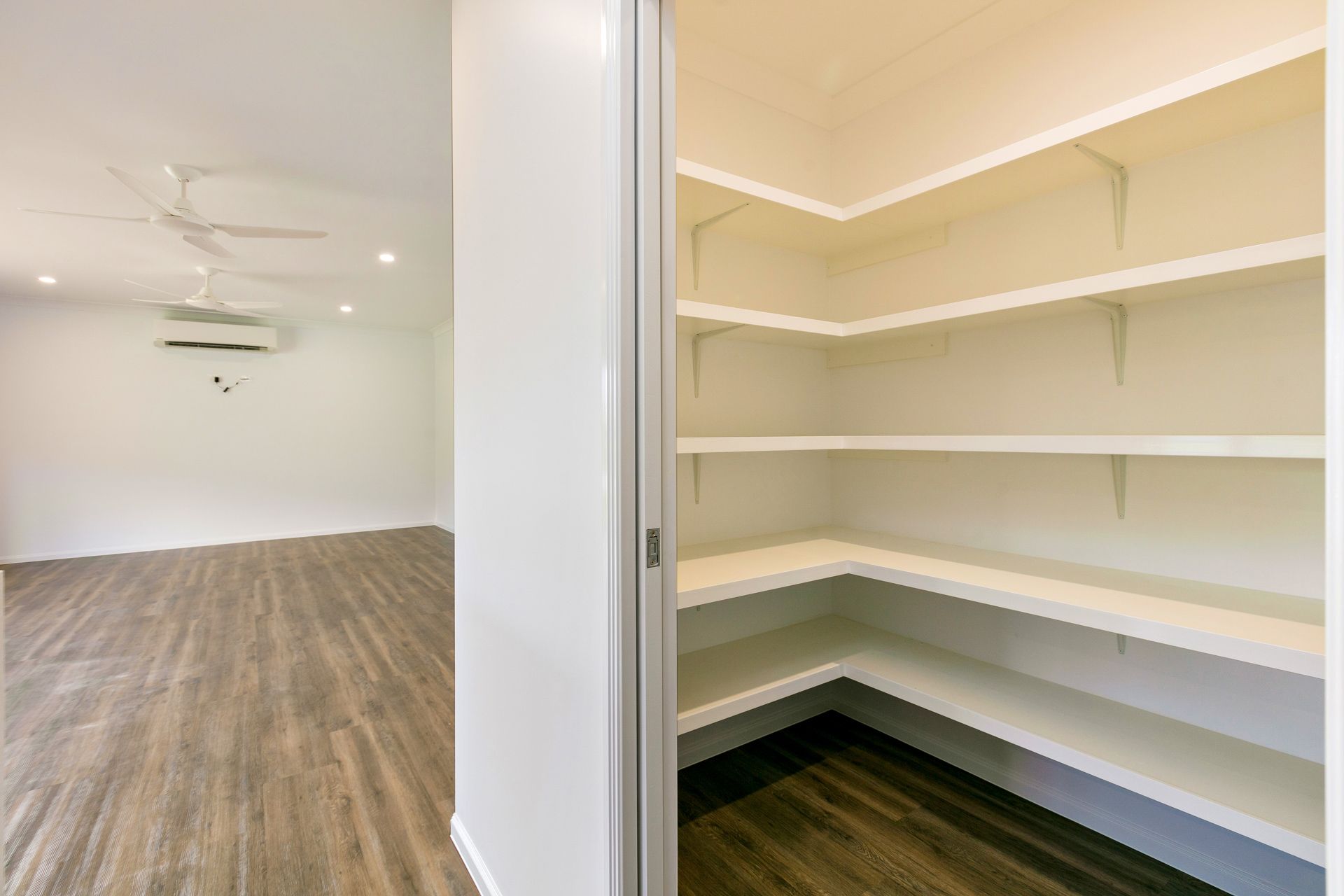 A Walk-in Pantry With White Shelves Next to a Brightly Lit — Ashlee Jones Homes in Gordonvale, QLD