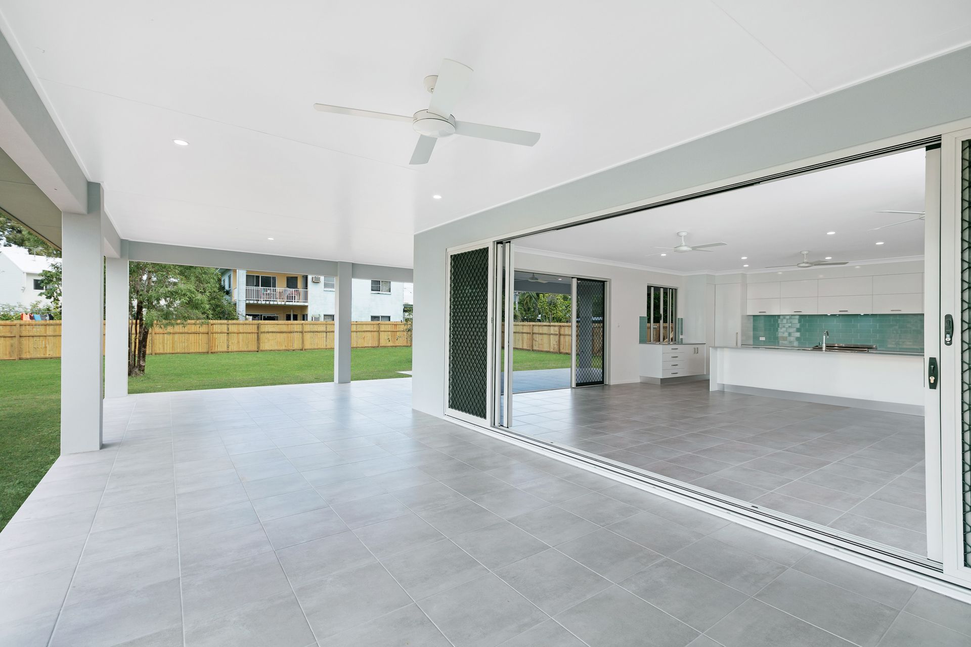 A Bright, Covered Patio With Gray Tile Flooring Transitions — Ashlee Jones Homes in Gordonvale, QLD