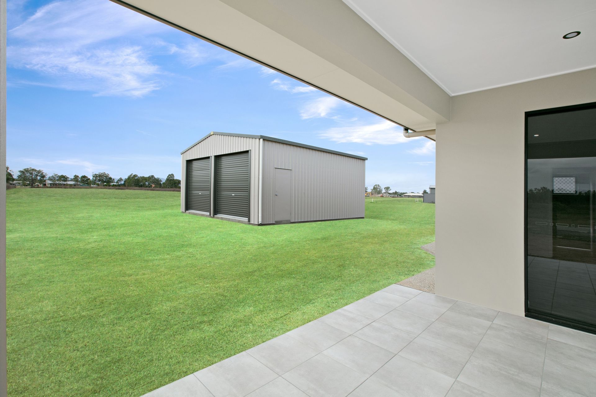 View From a Covered Concrete Patio Looking Across a Large Grassy Yard — Ashlee Jones Homes in Gordonvale, QLD