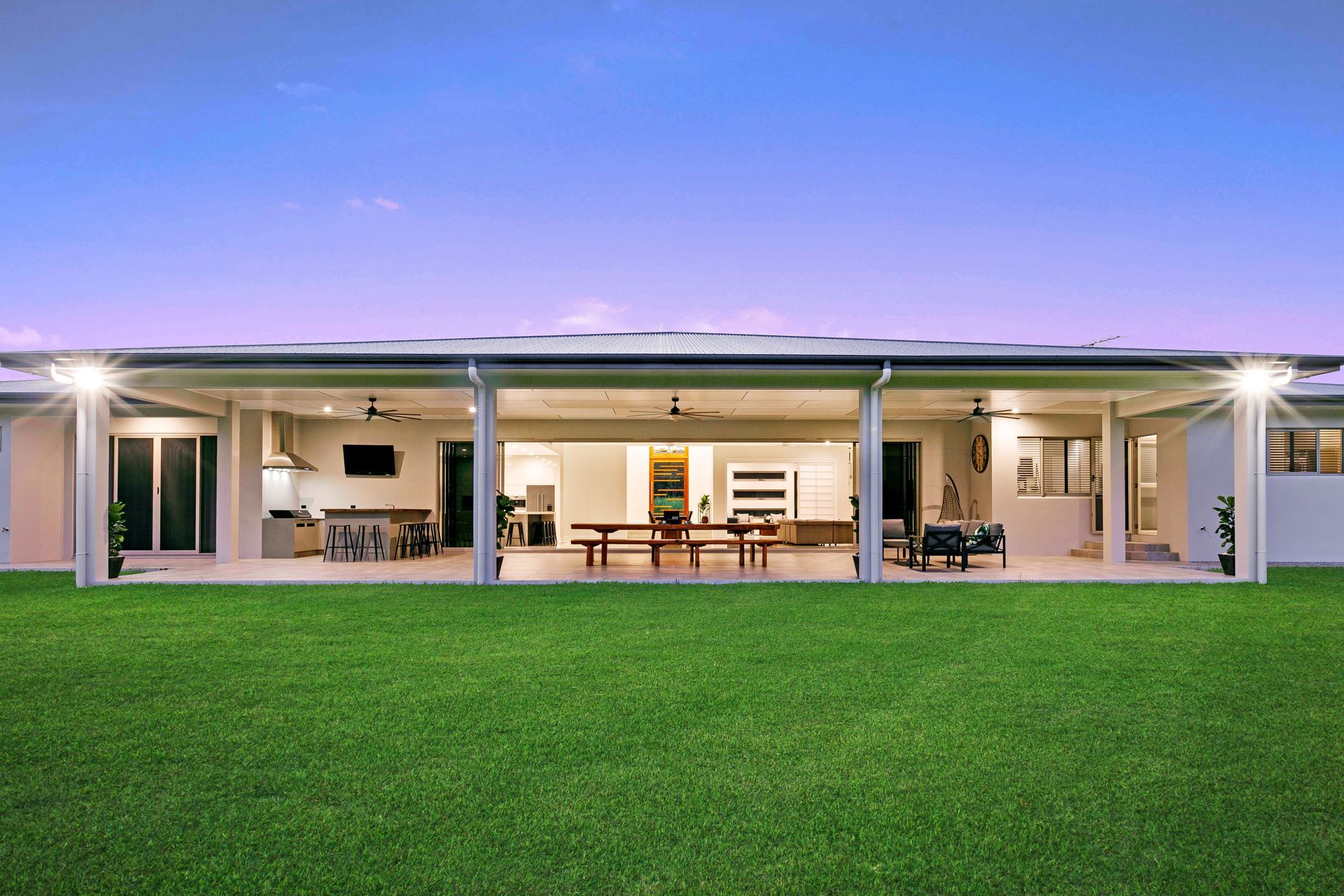 A Wide, Modern House Exterior at Dusk With a Large, Covered Outdoor Patio — Ashlee Jones Homes in Gordonvale, QLD