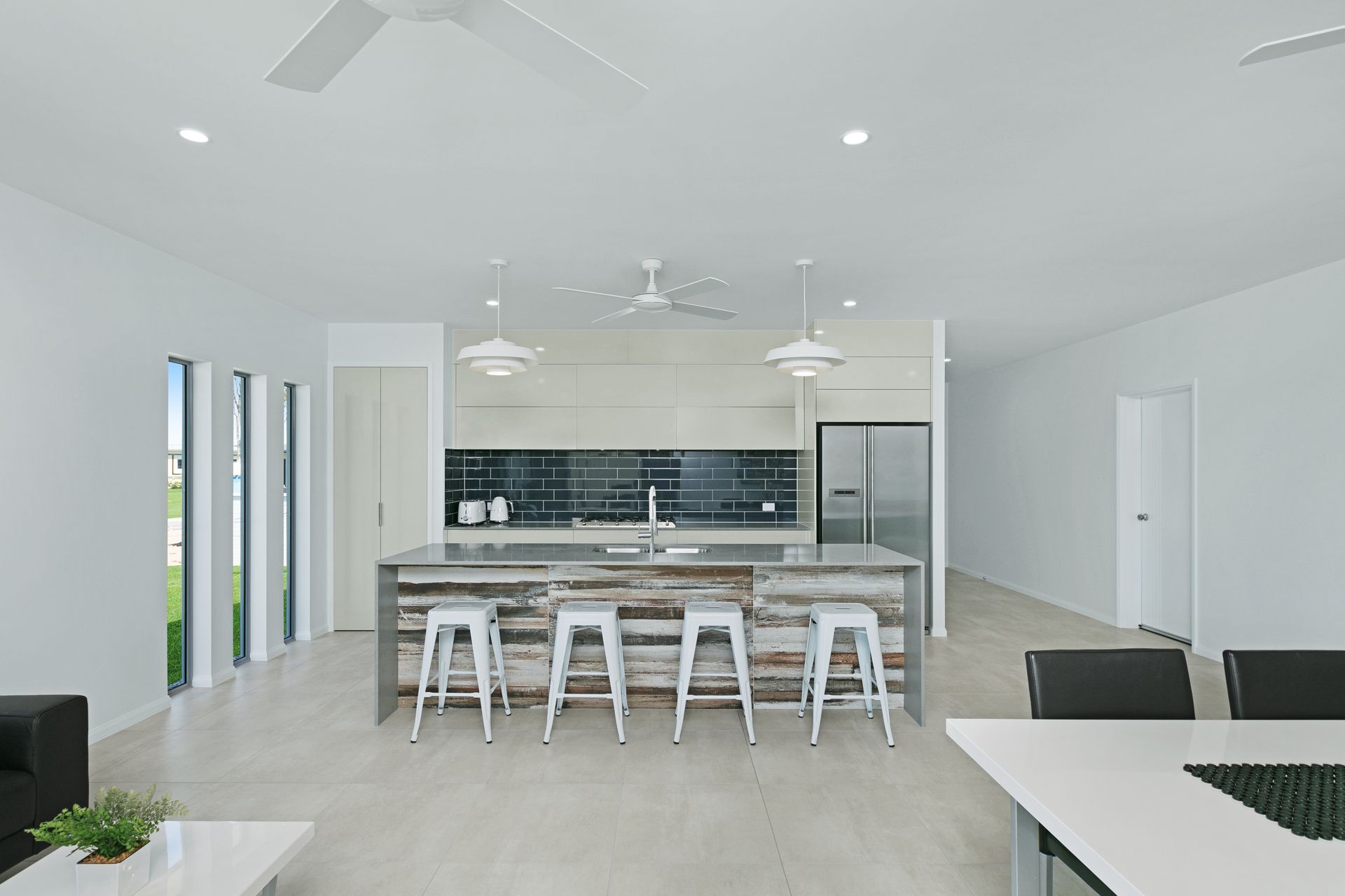 A Modern, Minimalist Kitchen Featuring a Rustic Wooden Island With White Stools — Ashlee Jones Homes in Gordonvale, QLD