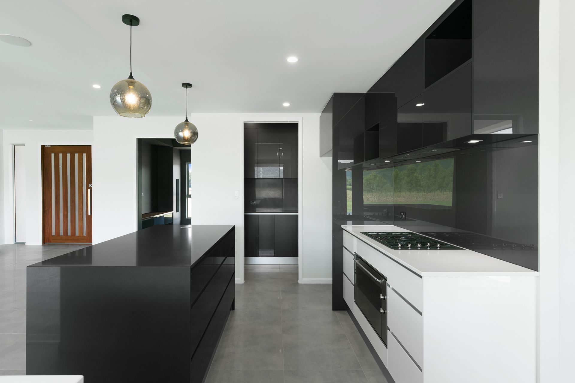 A Modern Kitchen With a Large Black Island, and a White Base Cabinets — Ashlee Jones Homes in Gordonvale, QLD
