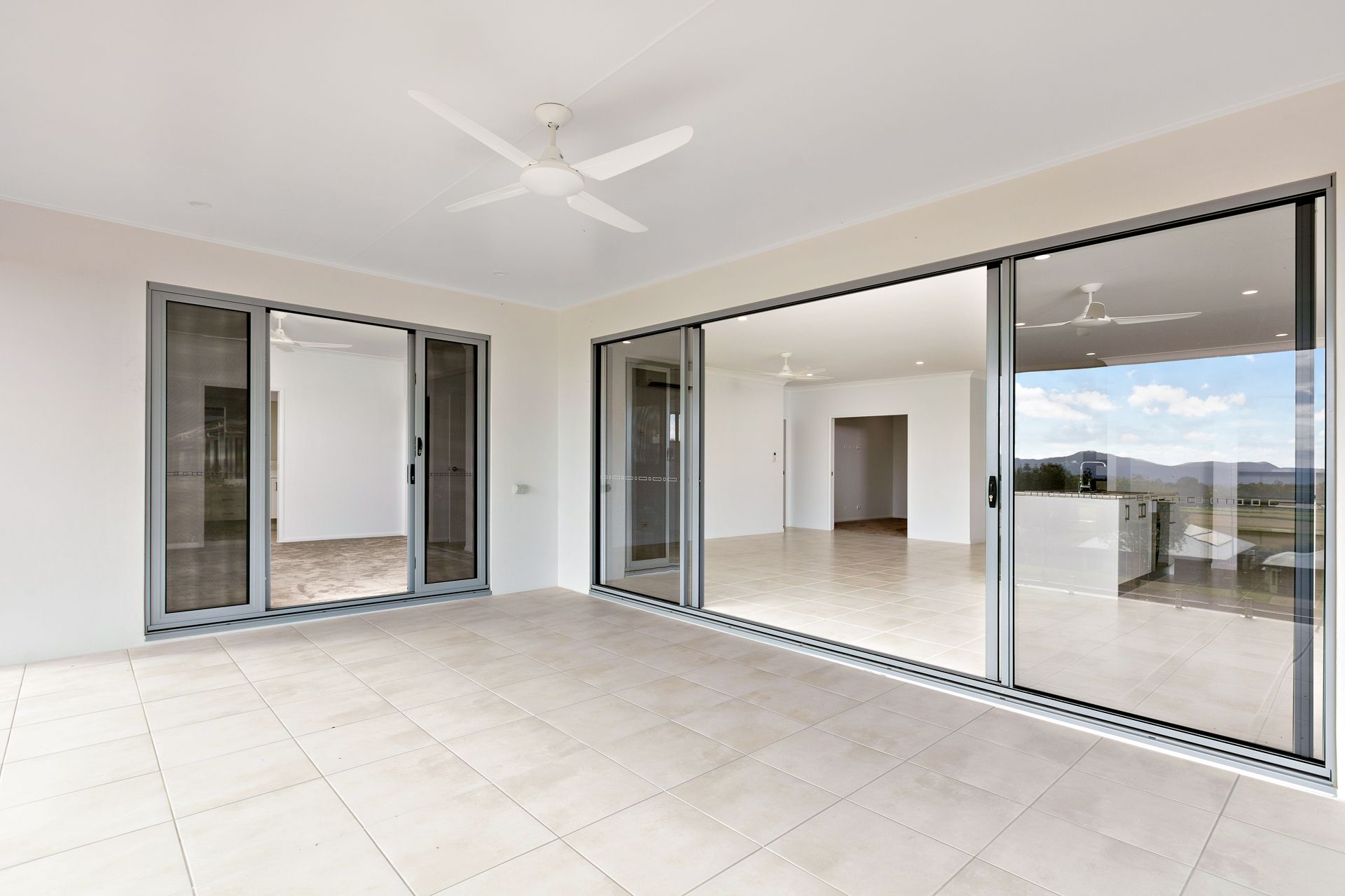 A Tiled Patio Featuring Large Glass Sliding Doors Opening Into a Spacious, Bright — Ashlee Jones Homes in Gordonvale, QLD