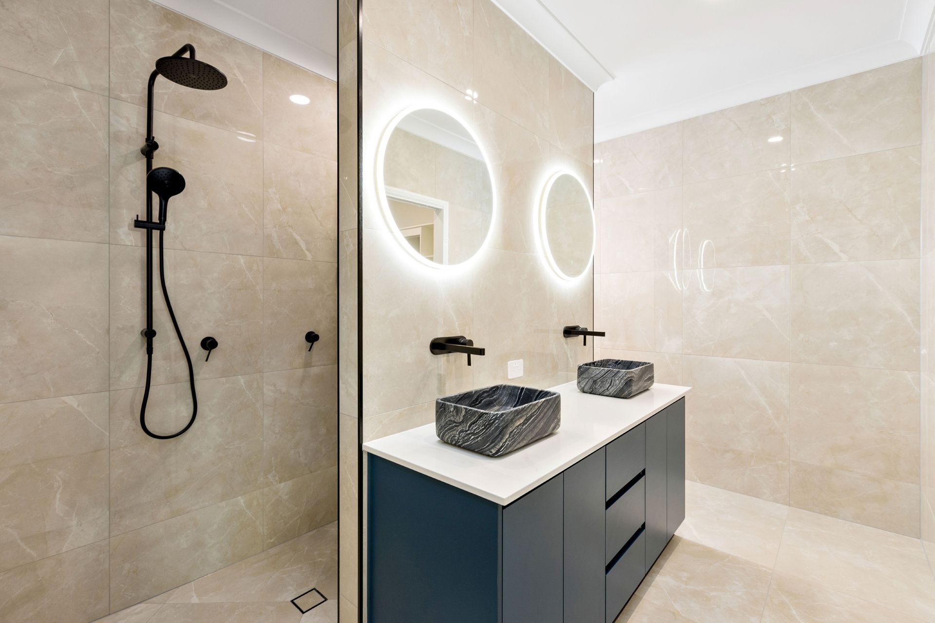 A Modern Bathroom With Light Beige Tiled Walls, a Black Double-sink Vanity — Ashlee Jones Homes in Gordonvale, QLD